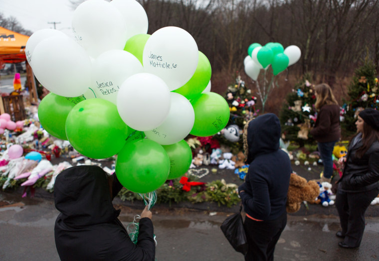 Kanga Kanh, left, and Channary Pich prepare to place 26 balloons at a makeshift memorial at the entrance to Sandy Hook Elementary School on Dec. 17 in Newtown, Conn.