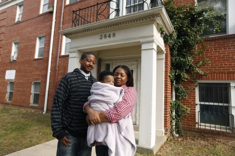 Michael Ponger, 30, stands next to his wife Stephanie, 31, and their four-month-old baby, Michael Jr, outside their apartment in Washington, D.C. Ponger makes $12 an hour as a part-time security guard.