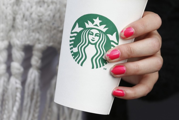 A woman holds a Starbucks takeaway cup in this October 24, 2012 file photo. Starbucks has asked workers in its Washington-area shops to write