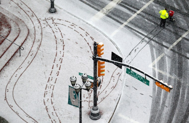 A person pushes a kart while salting the sidewalk at Military Park in downtown Newark, N.J., on Dec. 26. The National Weather Service forecast sustained winds of 15 to 20 mph along the coast in the afternoon, with gusts up to 40 mph. The storm is expected to dump a total of four to six inches on the area and also produce sleet and freezing rain. Other areas are expected to get between two and three inches of rain. A flood watch has been issued from Wednesday afternoon through Thursday morning.