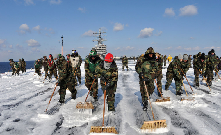 Sailors aboard the aircraft carrier USS Ronald Reagan wash down the flight deck to remove potential radiation contamination while operating off the coast of Japan providing humanitarian assistance in support of Operation Tomodachi on March 22, 2011.
