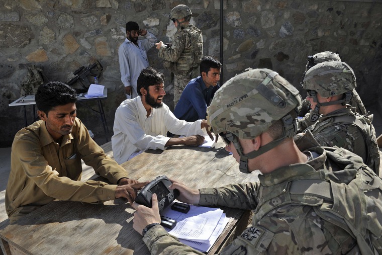 Pfc Lee Jarod (L), Pfc Wheeler Russel (C) and Charleston Robert from US army HHB 3-7 Field Artillery Regiment 3rd Bct 25th ID scann Afghans as part of Automated Biometric Identification System (ABIS) during a mission in Turkham Nangarhar bordering with Pakistan on September 27, 2011. Turkham is a border crossing town in the Nangarhar province of Afghanistan and the Khyber Agency of Pakistan's Federally Administered Tribal Areas.A decade of fighting in Afghanistan has since snowballed into a huge effort involving around 130,000 foreign troops from dozens of countries, with the resilient Taliban using homemade bombs and guerrilla tactics in a bid to undermine the Afghan government and the NATO mission. AFP PHOTO/Tauseef MUSTAFA. (Photo credit should read TAUSEEF MUSTAFA/AFP/Getty Images)