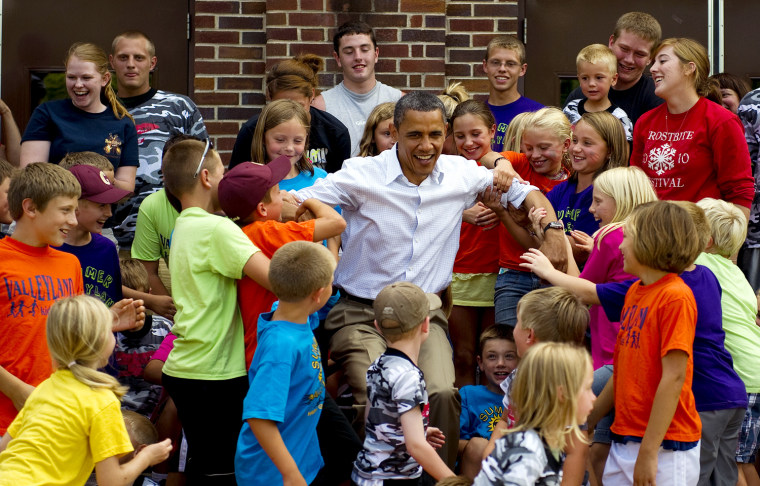 Summer camp students from Chatfield public schools help up US President Barack Obama (C) after they posed for a picture in front of the school in Chatfield, Minnesota, August 15, 2011 during his three-day bus tour in the Midwest centering on ways to grow the economy.      AFP PHOTO/Jim WATSON (Photo credit should read JIM WATSON/AFP/Getty Images)