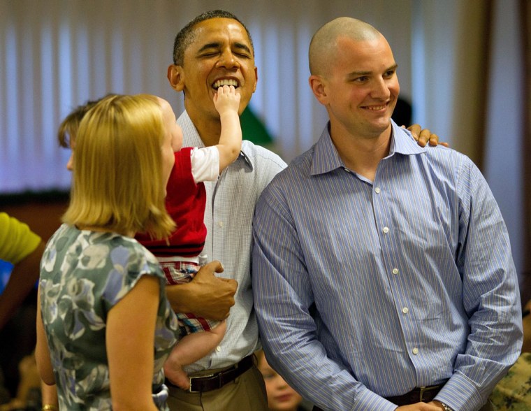 epa03043130 Eight month old Cooper Wall Wagner sticks his fingers in US President Barack Obama's mouth as the President (C) poses for a picture with Cooper's parents Greg (R) and Meredith Wagner (L) in Kaneohe, Hawaii 25 December 2011. The President and Mrs. Obama make their annual trip to greet current and retired members of the US military and their families as they eat a Christmas Day meal Anderson Hall mess hall at Marine Corps Base Hawaii. EPA/Kent Nishimura / POOL