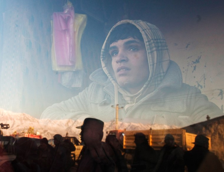 An Afghan boy who works at a bakery watches a protest outside his a window in Kabul February 24, 2012. Twelve people were killed on Friday in the bloodiest day yet in protests that have raged across Afghanistan over the desecration of copies of the Muslim holy book at a NATO military base with riot police and soldiers on high alert braced for more violence. REUTERS/Ahmad Masood (AFGHANISTAN - Tags: RELIGION CIVIL UNREST TPX IMAGES OF THE DAY)