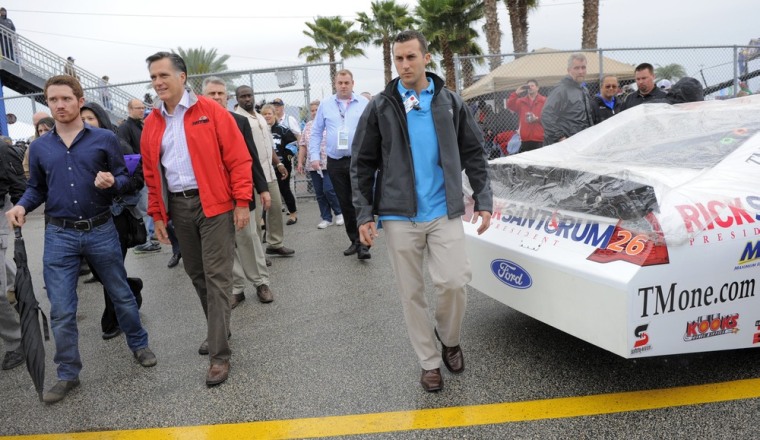Republican presidential candidate and former Massachusetts Governor Mitt Romney (2nd L) walks past the number 26 Ford, driven by Tony Raines, with advertising for Romney's opponent, Rick Santorum, during his appearance at the NASCAR Sprint Cup Series 54th Daytona 500 race at the Daytona International Speedway in Daytona Beach, Florida, February 26, 2012. REUTERS/Brian Blanco (UNITED STATES - Tags: SPORT MOTORSPORT POLITICS ELECTIONS)