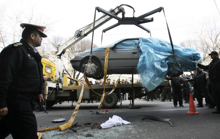 In this photo provided by the semi-official Fars News Agency, people gather around a car as it is removed by a mobile crane in Tehran, Iran, Wednesday, Jan. 11, 2012. Two assailants on a motorcycle attached magnetic bombs to the car of an Iranian university professor working at a key nuclear facility, killing him and wounding two people on Wednesday, a semiofficial news agency reported. (AP Photo/Fars News Agency, Mehdi Marizad)