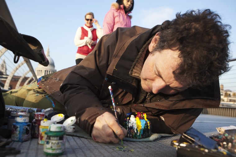 Artist Ben Wilson paints on a piece of discarded chewing gum on the Millennium Bridge, in London February 28, 2012. Wilson has painted miniature works of art on discarded chewing gum in various parts of London and Europe over the past seven years in an effort to