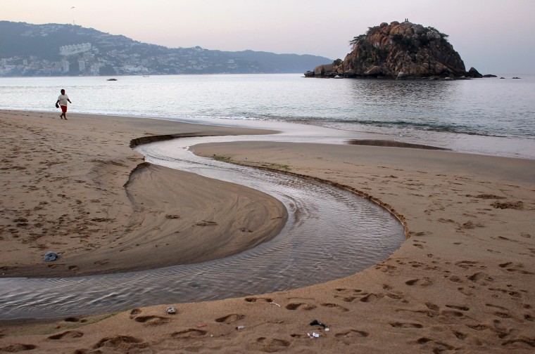 ACAPULCO, MEXICO - FEBRUARY 29: A lone person walks along the beach before sunrise on February 29, 2012 in Acapulco, Mexico. One of Mexico's top tourist destinations, Acapulco has suffered a drop in business, especially from foreign tourists due to drug violence in the last year. Toursim accounts for some 9 percent of Mexico's economy and about 70 percent of the output of Acapulco's state of Guerrero. (Photo by John Moore/Getty Images)