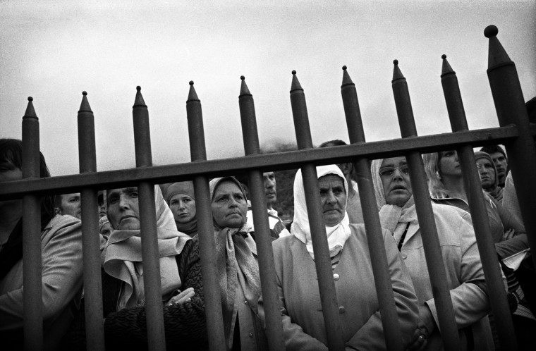 Bosnian Muslim women look through the bars as U.N. chief war crimes prosecutor Carla del Ponte arrives for a mass funeral at a cemetery near Srebrenica on July 11, 2007. Families of victims of the Srebrenica massacre gathered to bury more remains in an annual ceremony that has become the main event of their lives since the 1995 atrocity by Bosnian Serb forces.