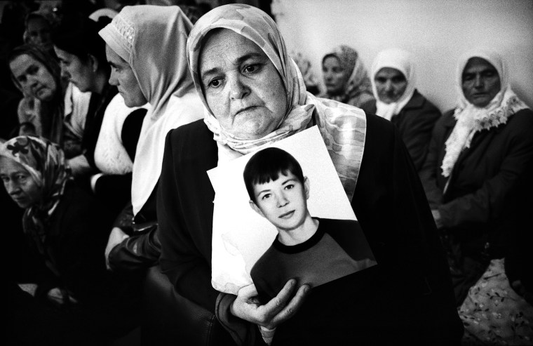 A woman holds a photo of her missing son as Bosnian Muslim relatives of the victims and survivors of the Srebrenica massacre meet with ex-Dutch peacekeepers in a former U.N base in Potocari on October 17, 2007. A group of Dutch ex-peacekeepers whose mission was to protect civilians in the U.N. safe haven of Srebrenica visited the site and met with survivors and relatives of victims.