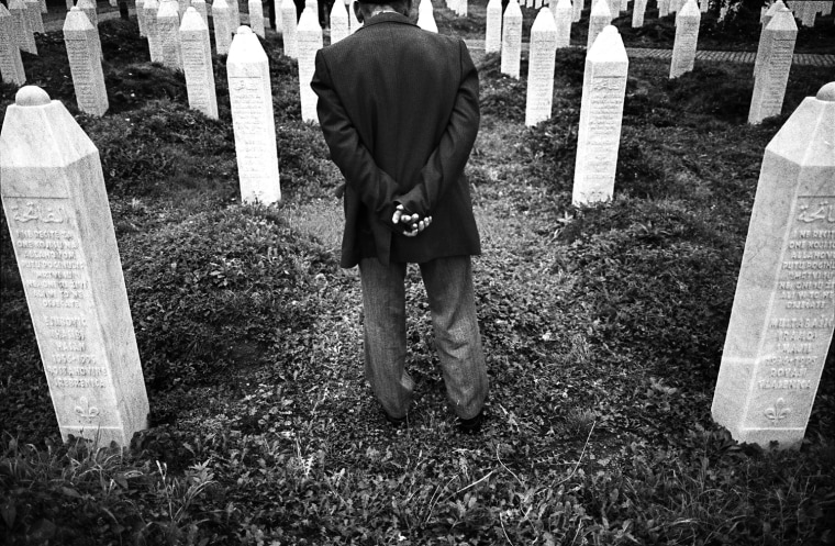 A Bosnian Muslim man searches for the name of a killed relative amongst gravestones of victims of the 1995 Srebrenica massacre, following morning prayers on the first day of Eid al-Fitr in Srebrenica on October 12, 2007.