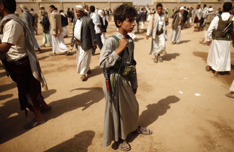 A boy stands among tribesmen, loyal to the al-Houthi Shi'ite rebel group, gathering in the northwestern Yemeni province of Saada, Yemen on July 11, 2012.