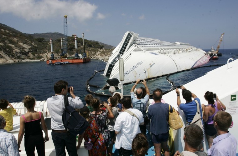 Tourists take photographs of the Costa Concordia wreckage as they arrive on a ferry to the Giglio Island, Italy, Thursday.