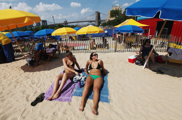 People relax in the sand at the Brooklyn Bridge Park pop-up pool on July 16, in the Brooklyn borough of New York City. A heat advisory was issued in the city again today as high temperatures were expected in the 90s the next three days.