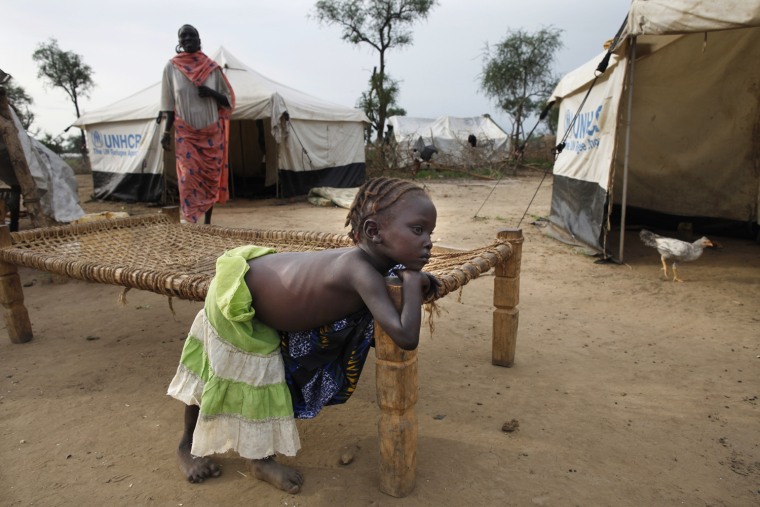 A Sudanese girl rests outside her tent as her mother stands nearby on July 16, 2012 in the Jamam refugee camp of South Sudan.
