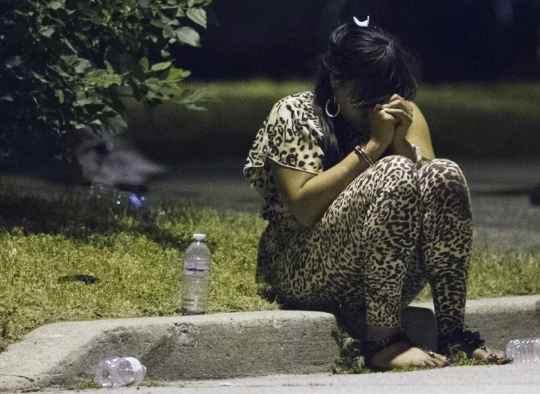 A woman sits on the curb wearing handcuffs following a shooting in Scarborough on July 17, 2012.
