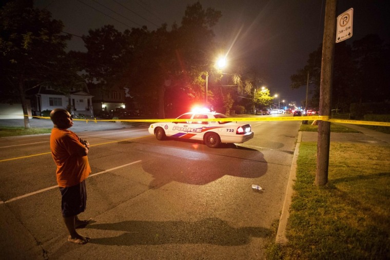 A man watches on at a crime scene following a shooting in Scarborough, a suburb in east Toronto, on July 17, 2012.