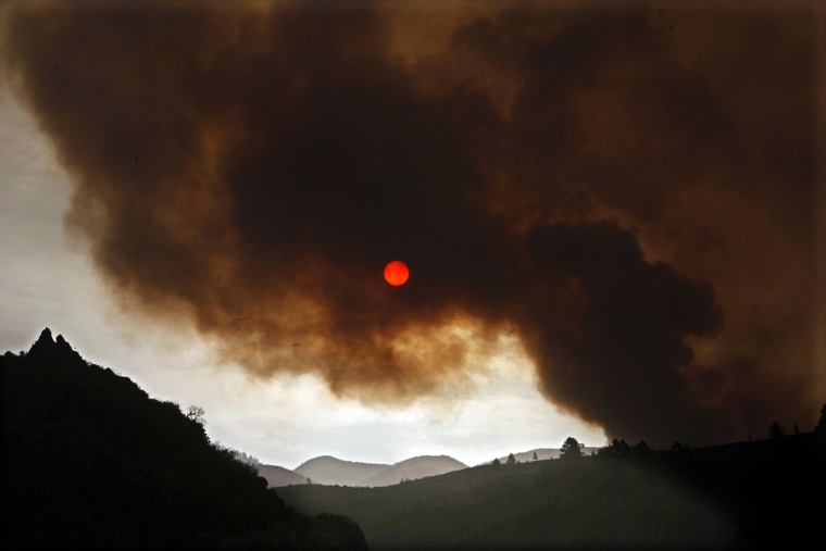 Photo taken on July 17, shows dark clouds of smoke billowing from a wildfire over the town of Tijoco Bajo, on the Spanish Canary island of Tenerife. A forest fire raging on the Spanish island reached the edge of a major tourist park on July 16, spewing thick smoke and red sparks. The fire broke out on July 15, 2012, prompting emergency services to evacuate 90 villagers from their homes overnight, and has spread over 1,800 hectares (2,700 acres), the regional government said.