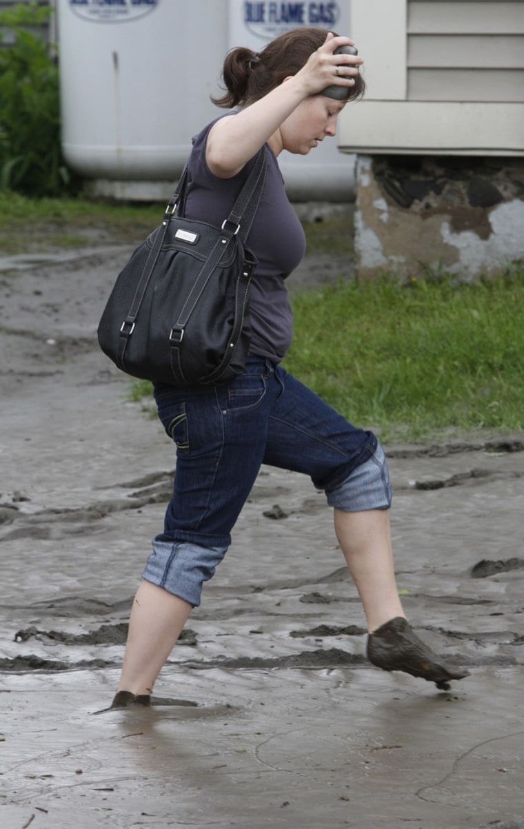 A woman walks through a mud-covered street on Friday, May 27, in Barre, Vt. Schools and roads are closed across central Vermont as heavy overnight rains caused flooding that overflowed riverbanks. A Vermont Emergency management official said early Friday almost 150 people were in three shelters in Barre, Montpelier and Berlin. The Vermont National Guard sent emergency response teams and high water vehicles to the area to help local and state emergency management officials. The flooding was caused by heavy overnight rains and more rain is forecast.