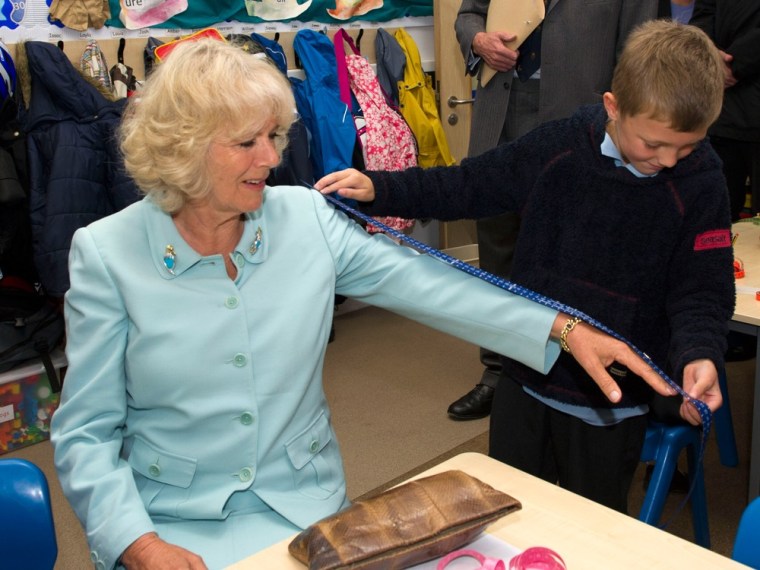 \"Why yes, you'd make a great addition to the Palace sweatshop.\" No, not really. Camilla has her arm measured by a 7-year-old as she meets children during a visit to the Five Islands School on July 3 in St Mary's, England.