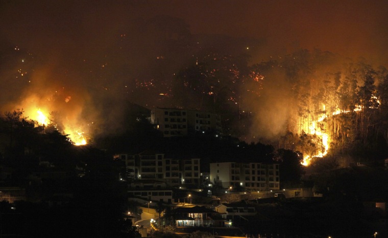 Flames move towards houses in Funchal, on the Portuguese island of Madeira July 18, 2012. More than 1000 firefighters are trying to extinguish forest fires after temperatures rose up to 104 degrees Fahrenheit in several areas of the country.