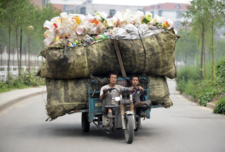 A motor tricycle loaded with recyclable plastic bottles drives along a street in Taiyuan, Shanxi province, China on July 18, 2012.