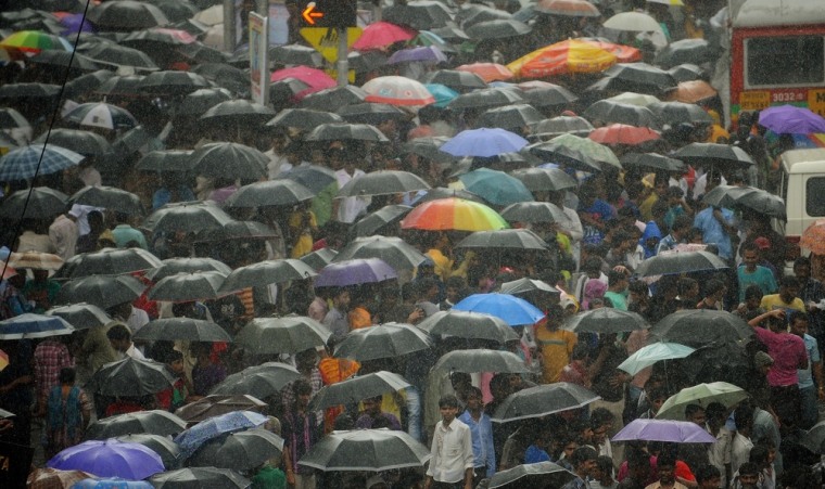 Huge crowds shield themselves with umbrellas in heavy rain during the funeral procession of Rajesh Khanna in Mumbai on July 19, 2012.