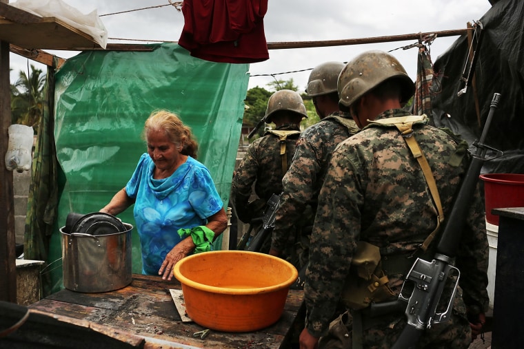 A woman dismantles her shack as military personnel move through during an eviction on July 20.
