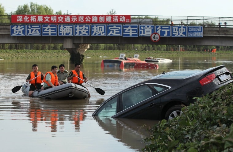 A rescue boat approaches a partially submerged car on a flooded highway after heavy rainfalls hit Fangshan District in Beijing, July 22, 2012.