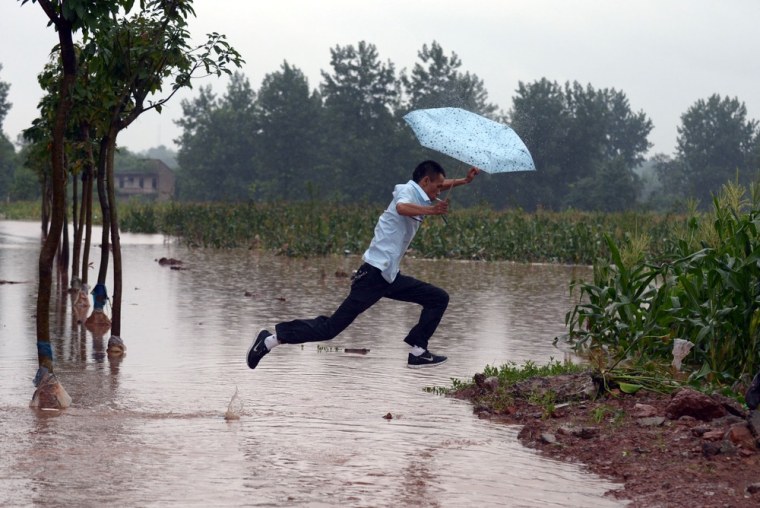 A man jumps across a flooded path on the outskirts of Chongqing, China on July 22, 2012. More torrential rain is forecast in China's northeast and southwest.