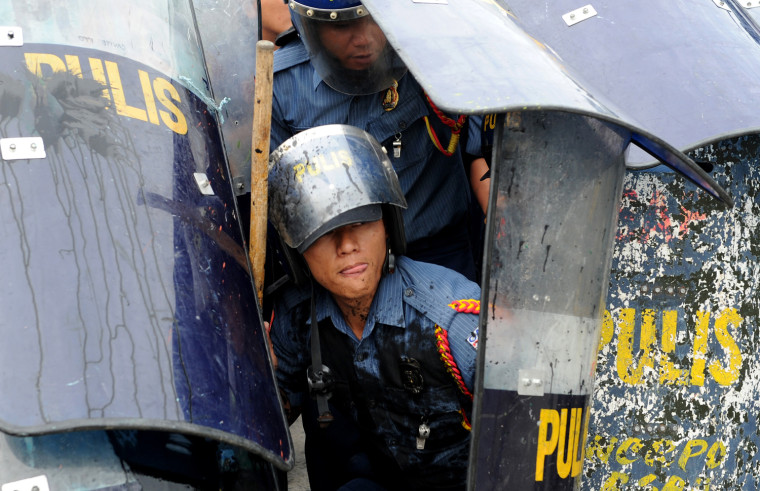 Policemen hide under their shields as anti-government protesters throw rocks during a demonstration against the state of the nation address of Philippine President Benigno Aquino near the legislature building in Manila on Monday..