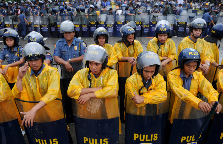 Policemen wear raincoats as they form a barricade during a demonstration against Philippine President Benigno Aquino's state of the nation address near the legislature building in Manila on Monday, July 23.