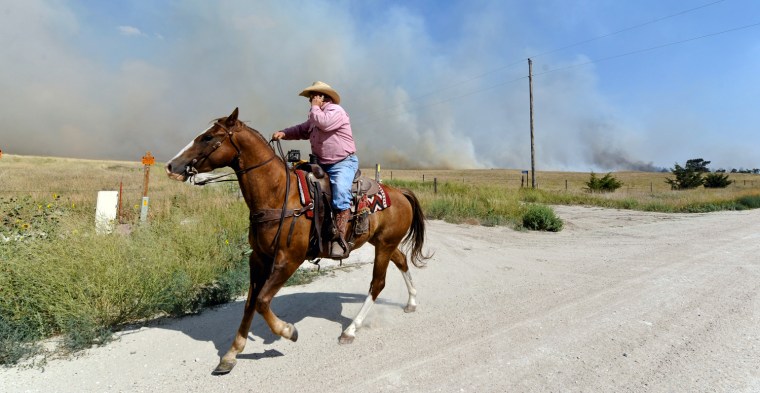 Dick Callfield uses a cell phone on horseback while trying to get some cattle moved to a clear pasture Monday July 23, at the Fairfield Creek fire near Springview, Neb. The sprawling fire, sparked Friday by lightning, had charred at least 50,000 acres by Monday morning and it wasn't clear how much of the fire had been contained.