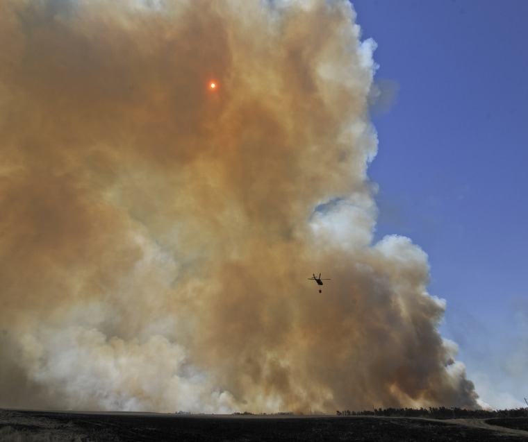 A Nebraska National Guard helicopter flies to drop water Monday July 23, at the Fairfield Creek fire near Springview, Neb. The sprawling fire, sparked Friday by lightning, had charred at least 50,000 acres by Monday morning and it wasn't clear how much of the fire had been contained.