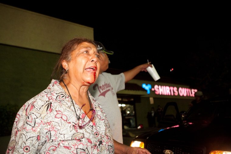 An injured pedestrian cries out to end the destruction of local properties after violence erupted between police officers and protesters at Anaheim City Hall on July 24, 2012.