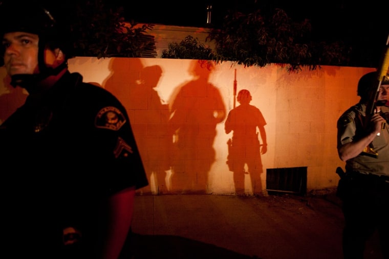 Police officers stand guard after protesters set fire to a nearby trash bin during a demonstration to show outrage at the fatal shooting of Manuel Angel Diaz, at Anaheim City Hall on July 24, 2012 in Anaheim, California. Diaz was fatally shot on July 21 by an Anaheim police officer and has sparked days of protests by the angered community.