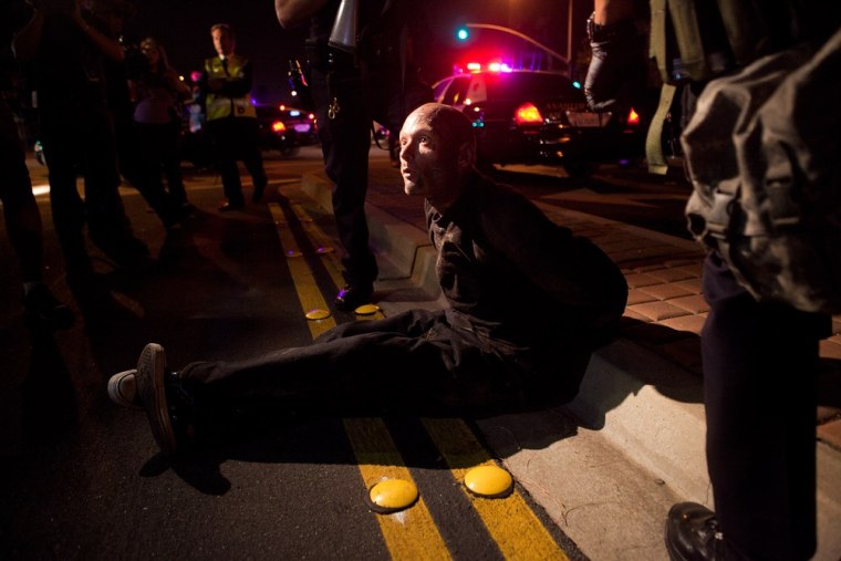 Police officers take a man into custody after he refused to disperse during a demonstration at Anaheim City Hall on July 24, 2012.