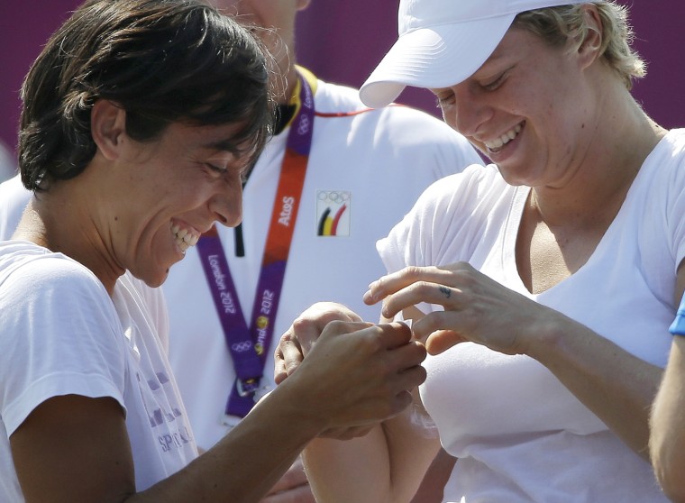 Tennis players Francesca Schiavone of Italy, left, laughs with Kim Clijsters of Belgium as they exchange pins at the All England Lawn Tennis Club at Wimbledon, London during training at the 2012 Summer Olympics, Thursday, July 26, 2012.