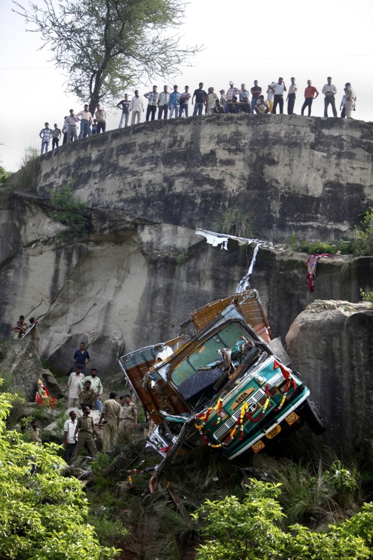 Police officers inspect the wreckage of a truck after it veered off a mountain road and plunged into a gorge about 65 kilometers southwest of Jammu, India, on July 27, 2012.