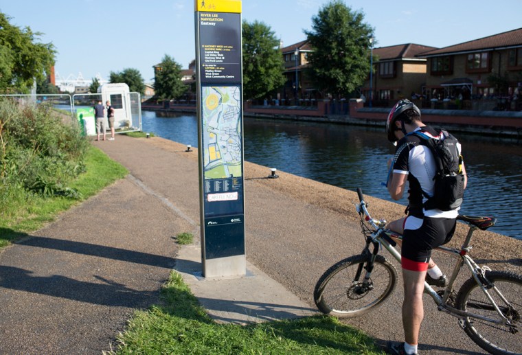 A cyclist uses his phone to help navigate around the security gate blocking the bike path along the western edge of the Olympic Park, Saturday, July 21, 2012 in London.
