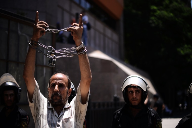 An Egyptian man chains his own wrists as he takes part in a demonstration against military trials outside Cairo's administrative court on July 30, 2012.