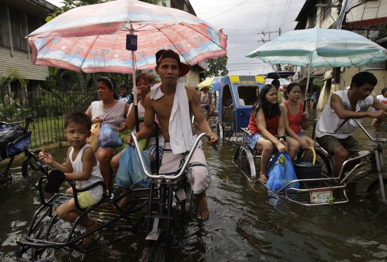 Residents ride a pedicab along a flooded street in Valenzuela city, north of Manila, Philippines on July 31, 2012.