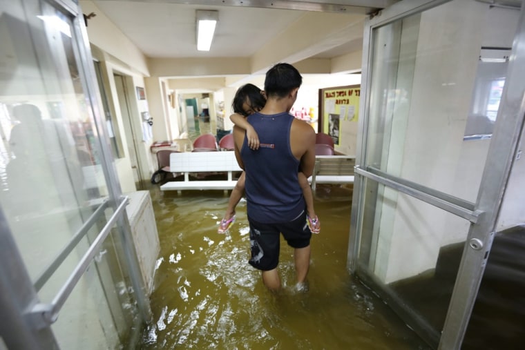 A man carries his child through the flooded emergency room of a hospital in Valenzuela City on July 31, 2012.