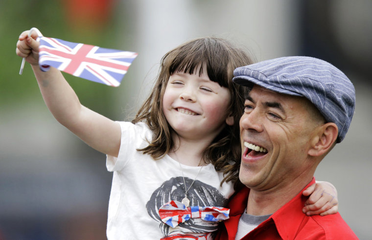 A man holding a girl waving a Union flag stands among other spectators near Parliament Square for a glimpse of Queen Elizabeth, in London on June 5.