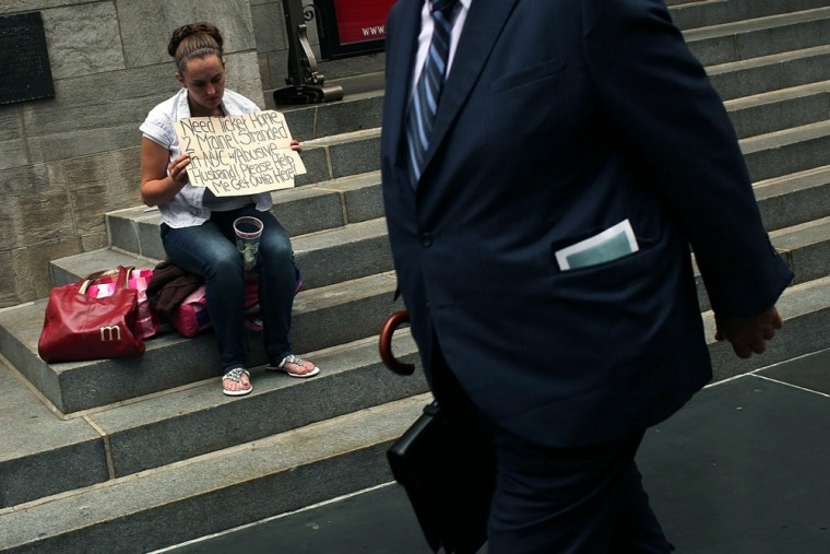 Scene form New York City: A businessman walks by a homeless woman begging for money. New York tops the list of states where the wealth gap is greatest.