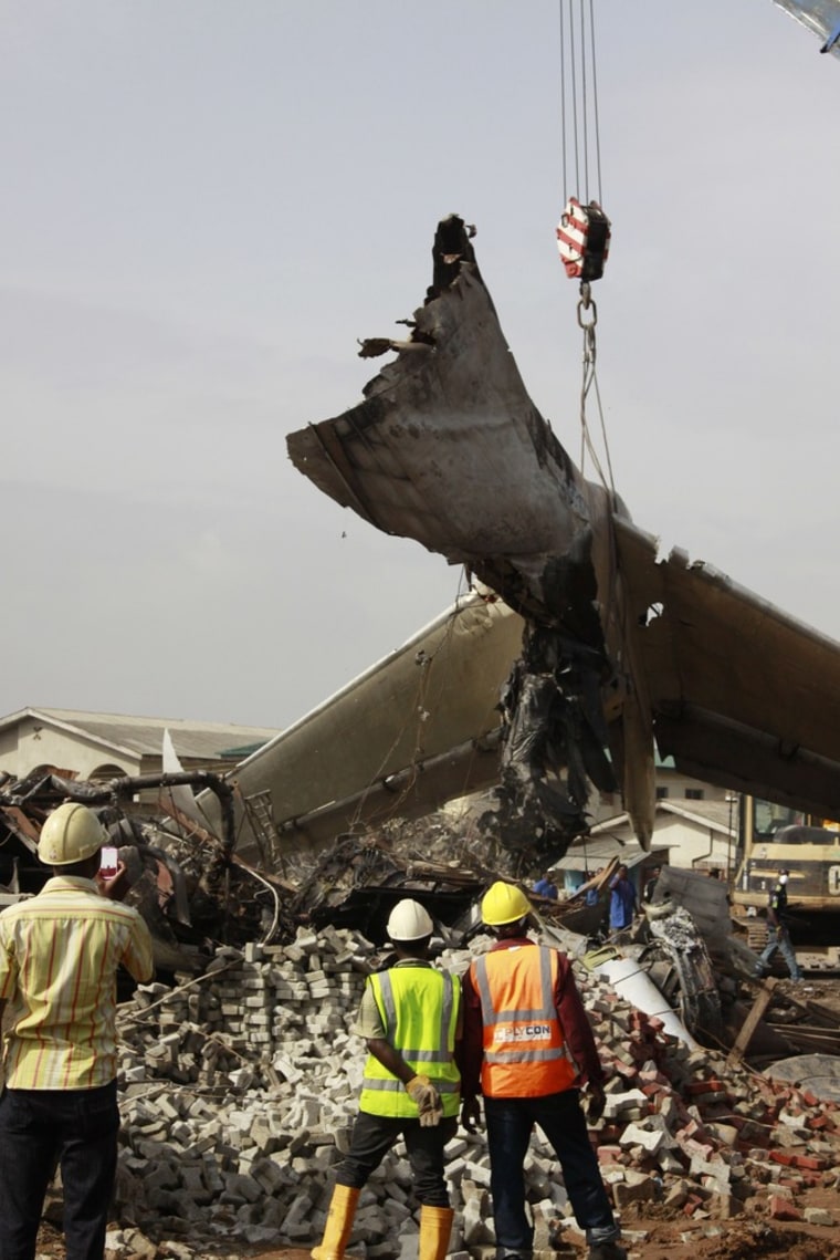 Rescue workers watch as a crane lifts the wreckage of Sunday's plane crash in Lagos, Nigeria.