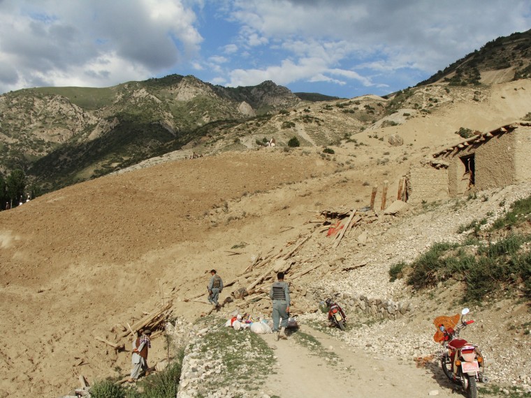 Afghan national police stand at the site of a landslide that hit the Baghlan province, north of Kabul, Afghanistan on June 11, 2012.