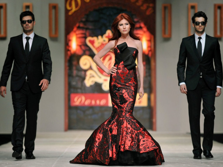 Russian ex-spy Anna Chapman, center, walks a Turkish catwalk flanked by two men posing as secret agents at a fashion show in Antalya, Turkey.