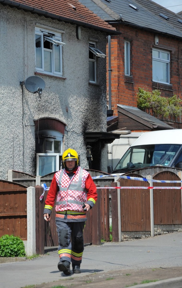 A firefighter walks past the fire-damaged house in which six children died in Derby, central England.
